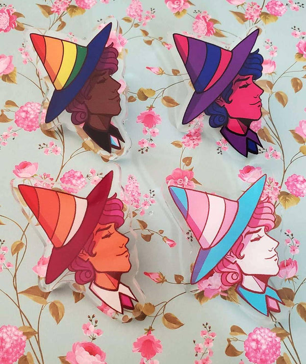 A set of four acrylic pins with colorful character designs on a floral background.