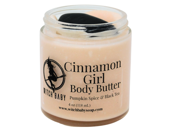 4 oz glass jar filled with autumnal orange body butter and topped with black tourmaline. Clear label reads: Cinnamon Girl Body Butter. Pumpkin Spice & Black Tea. 