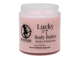 front view of pink lucky #7 body butter with a clear label that reads: Lucky #7 body butter. Merlot & rosewater. 