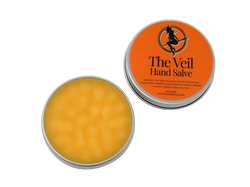 open tin showing orange salve inside. orange label on lid reads The Veil Hand Salve. with ingredients below