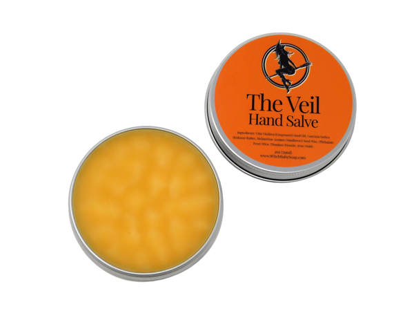 open tin showing orange salve inside. orange label on lid reads The Veil Hand Salve. with ingredients below