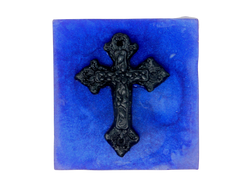 A squared shaped purple soap that smells like violets and sugar topped with a black cross.