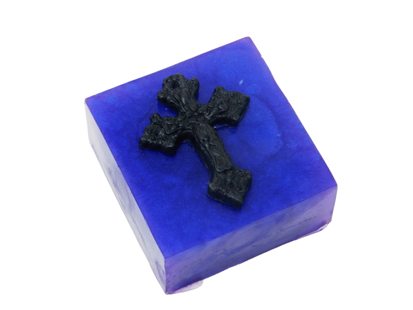 A squared shaped purple soap that smells like violets and sugar topped with a black cross.