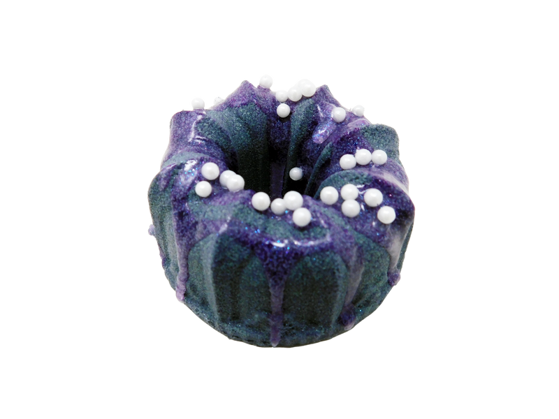 dark indigo bundt cake shaped bath bomb drizzled with purple soap with pearlescent sprinkles on top