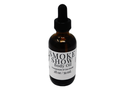 Smoke Show Body oil in a 2 oz glass dropper bottle with a white label that reads: Smoke Show Body Oil. Pomegranate & Gun Smoke.