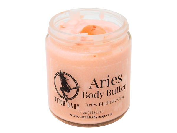 4 oz glass jar filled with orange-y pink body butter topped with carnelian. Clear label reads: Aries Body Butter. Aries Birthday Cake. 