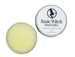 Circular tin containing hand salve. Label says Basic Witch Hand Salve. 