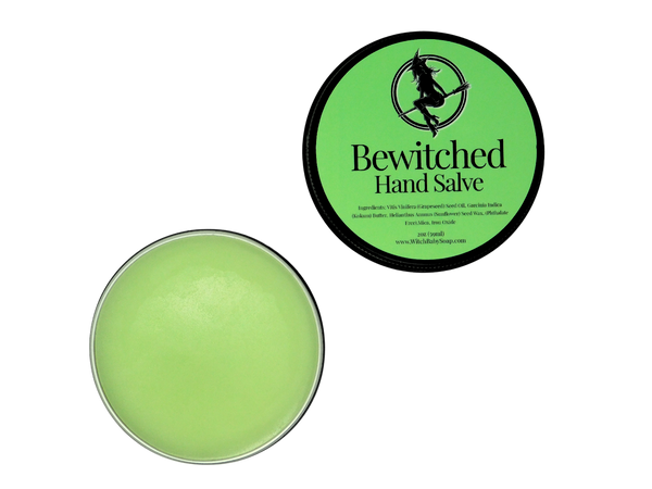 2 oz black tin of Bewitched Hand Salve with green label pictured with the lid off to show the green hand salve inside 