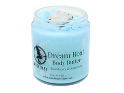 Sky blue body butter in 4 oz glass jar topped with lid removed to reveal rainbow moonstone. Label reads: Dream Boat Body Butter. Blackberry & Sugarcane. 