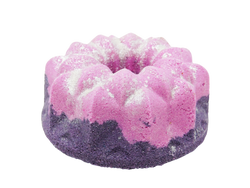 purple and pink bundt cake shaped bath bomb with white glitter dusted on top