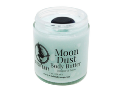 Moon Dust Body Butter is pictured on a white background. It is an icy blue body butter in a glass jar without a lid to show that it is topped with a blue goldstone crystal. Label is clear and reads: Moon Dust Body Butter. Juniper & Snow. 4 oz (118 mL). www.witchbabysoap.com